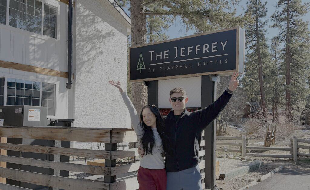 South Lake Tahoe hotel deals at The Jeffrey Hotel two happy guests standing in front of the jeffrey hotel sign in south lake tahoe