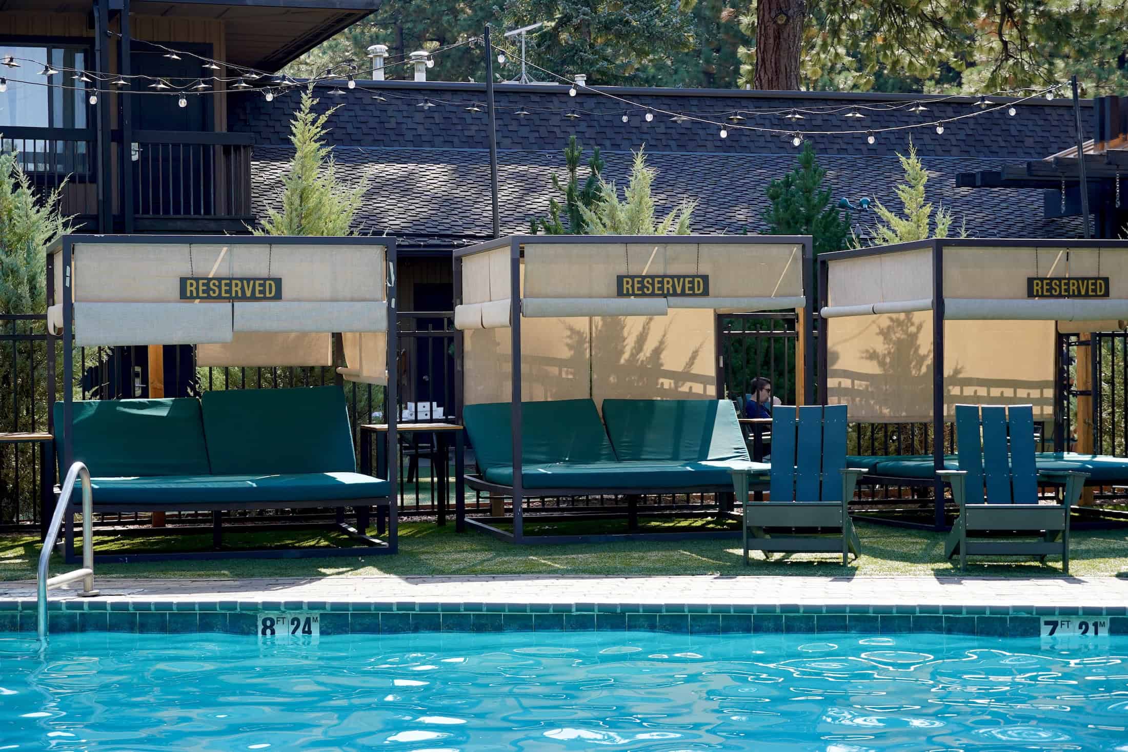A pool with lounge chairs and cabanas in the background